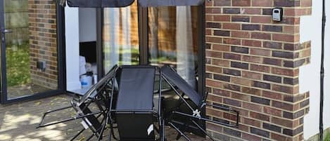 A modern outdoor seating area with a table and chairs, a large umbrella, and a brick wall.
