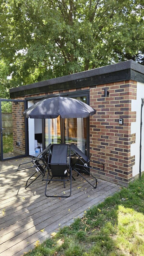 A modern outdoor seating area with a table and chairs, a large umbrella, and a brick wall.