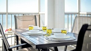 Une table à manger dressée avec des assiettes, des couverts et des verres, sur un balcon offrant une vue panoramique.