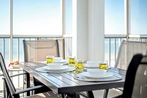A dining table with plates, cutlery, and glasses on a balcony with a view. - Your Fort Myers Beach Escape | Relax & Unwind (Fort Myers Beach)