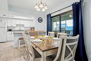 Ein Essbereich mit einem Holztisch, gedeckt für vier Personen, weißen Stühlen und Blick durch eine Glastür.