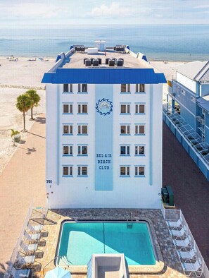 Ein Strandhotel mit Pool, Liegestühlen und Blick auf den Ozean.