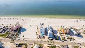 An aerial view of a beachside hotel with multiple buildings, a parking lot, and a clear view of the ocean. - Private 2BR Stay | Your Fort Myers Beach Getaway (Fort Myers Beach)