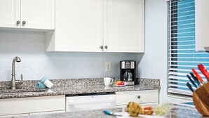 A kitchen with white cabinets, a granite countertop, a coffee maker, and a window with blinds. - Private 2BR Stay | Your Fort Myers Beach Getaway (Fort Myers Beach)