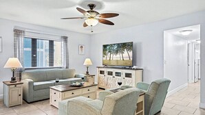 A living room with a sofa, chairs, a coffee table, a television, and a ceiling fan. - Private 2BR Stay | Your Fort Myers Beach Getaway (Fort Myers Beach)