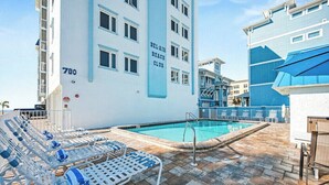 A pool area with lounge chairs and a building labeled 'BEL-AIR BEACH CLUB' with the number 780. - Private 2BR Stay | Your Fort Myers Beach Getaway (Fort Myers Beach)