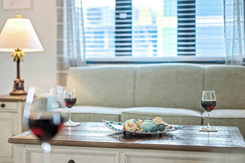 A dining table with a plate of food and two glasses of red wine.