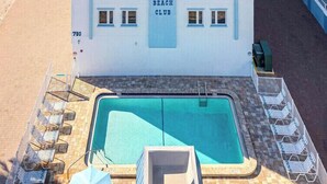 A beachfront hotel with a pool, multiple balconies, and a beach view. - Poolside 2BR Condo with Balcony near Beach Pier (Fort Myers Beach)