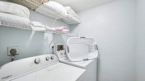 A laundry area with a Whirlpool washer, a drying rack, and a basket. - Poolside 2BR Condo with Balcony near Beach Pier (Fort Myers Beach)