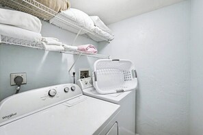 Ein Waschbereich mit einer Whirlpool-Waschmaschine, einem Wäscheständer und einem Wäschekorb.