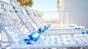 A row of white lounge chairs with blue cushions, arranged outdoors. - Poolside 2BR Condo with Balcony near Beach Pier (Fort Myers Beach)