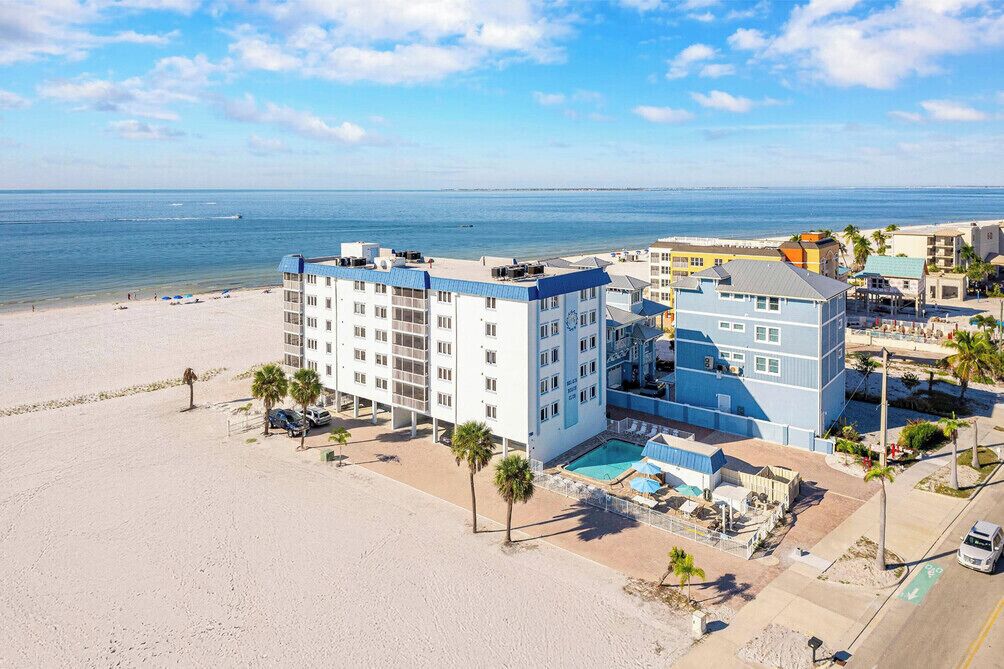 Ein Strandhotel mit mehreren Gebäuden, einem Swimmingpool und Blick auf den Strand.