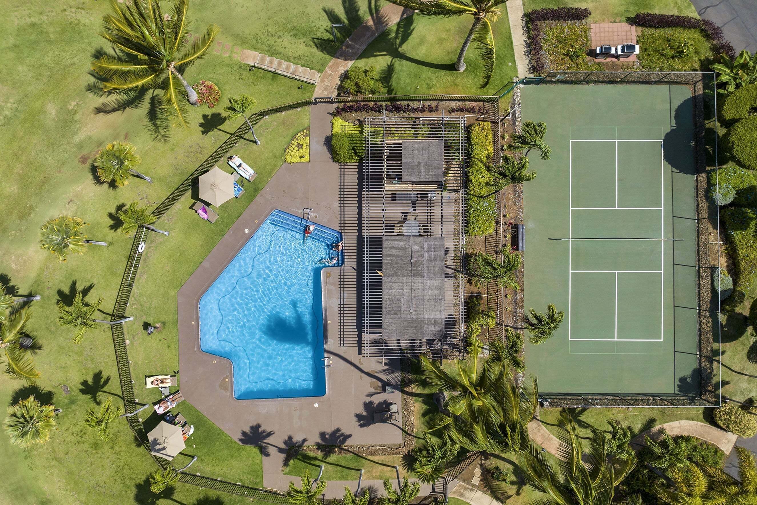 Vista aérea de una propiedad con piscina, cancha de tenis y abundante vegetación.