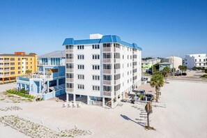 Ein mehrstöckiges Hotel mit Balkonen, gelegen in Strandnähe mit einem sandigen Bereich davor.