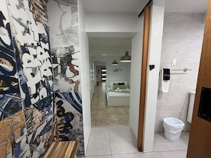 Un pasillo con una cama, un bote de basura y una pared con grafitis.