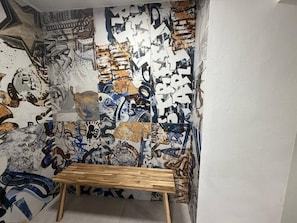 Una habitación con un muro cubierto de grafitis y un banco de madera.