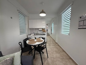 A narrow hallway leading to a kitchen and dining area with a round table and chairs. - Modern Santurce Apartment Near Beaches for 4 (San Juan de Puerto Rico)