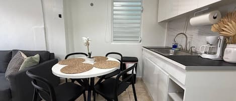 Eine kompakte Küche mit Essbereich, einer Couch und einem Fenster mit Jalousien.