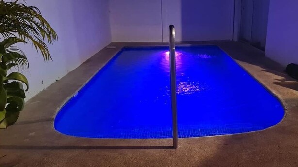 En swimmingpool med en metallstege, omgiven av väggar och ett betonggolv.