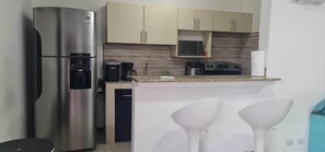 A compact kitchen with a stainless steel refrigerator, a microwave, and a coffee maker.
