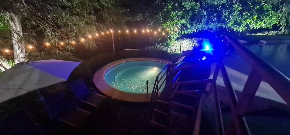 A hot tub surrounded by trees, with a ladder leading up to it.