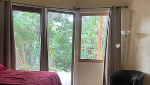 A room with a bed, a chair, and a view of greenery through a window. - Beautiful private villa with lovely gardens and trees (Santiago Atitlán)