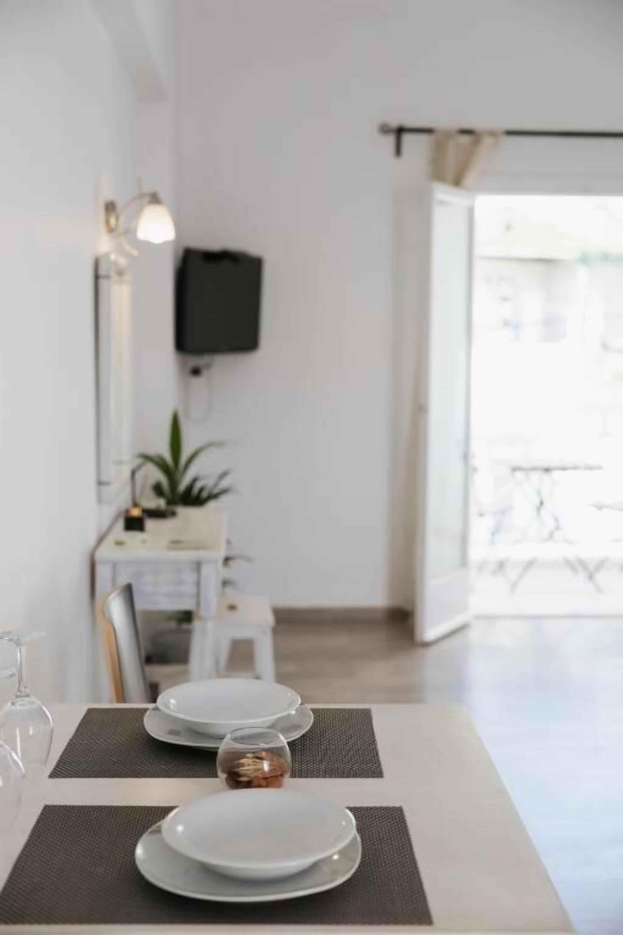 Zona pranzo con un tavolo apparecchiato per due, una televisione a muro e vista all'esterno.