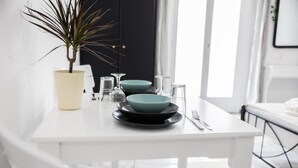 A white dining table with a potted plant, teal plates, and clear glassware. - White Wave Studios (santorini)