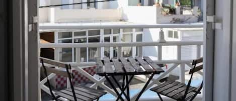 Un balcon ouvert avec une table et des chaises, donnant sur un paysage montagneux.