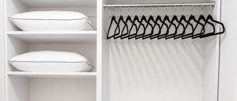 A white closet with shelves for folded clothes and a hanging rod for garments.