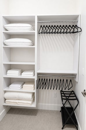 A white closet with shelves for folded clothes and a hanging rod for garments. - Stylish West Midtown Retreat - Pool & Balcony (Atlanta)