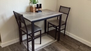 Uma mesa de jantar com duas cadeiras, uma pequena planta e um castiçal sobre a mesa.