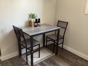 A dining table with two chairs, a small plant, and a candle holder on the table.