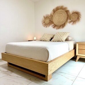 A bedroom with a wooden bed frame, a bedside table, a lamp, and wall art. - Casa Legaspi, Perfect for Work and Relaxation in GDL (Guadalajara)