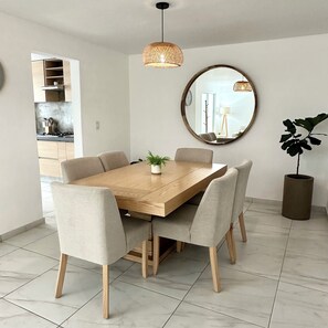 A dining area with a wooden table, six chairs, a hanging light fixture, a round mirror, and a potted plant. - Casa Legaspi, Perfect for Work and Relaxation in GDL (Guadalajara)