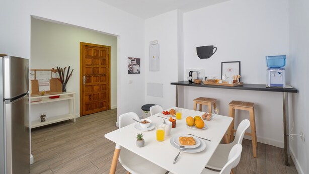 Una cocina moderna con armarios blancos, un refrigerador, una cafetera y un dispensador de agua.