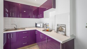 Una cocina moderna con armarios morados, un microondas y un cartel de bienvenida.