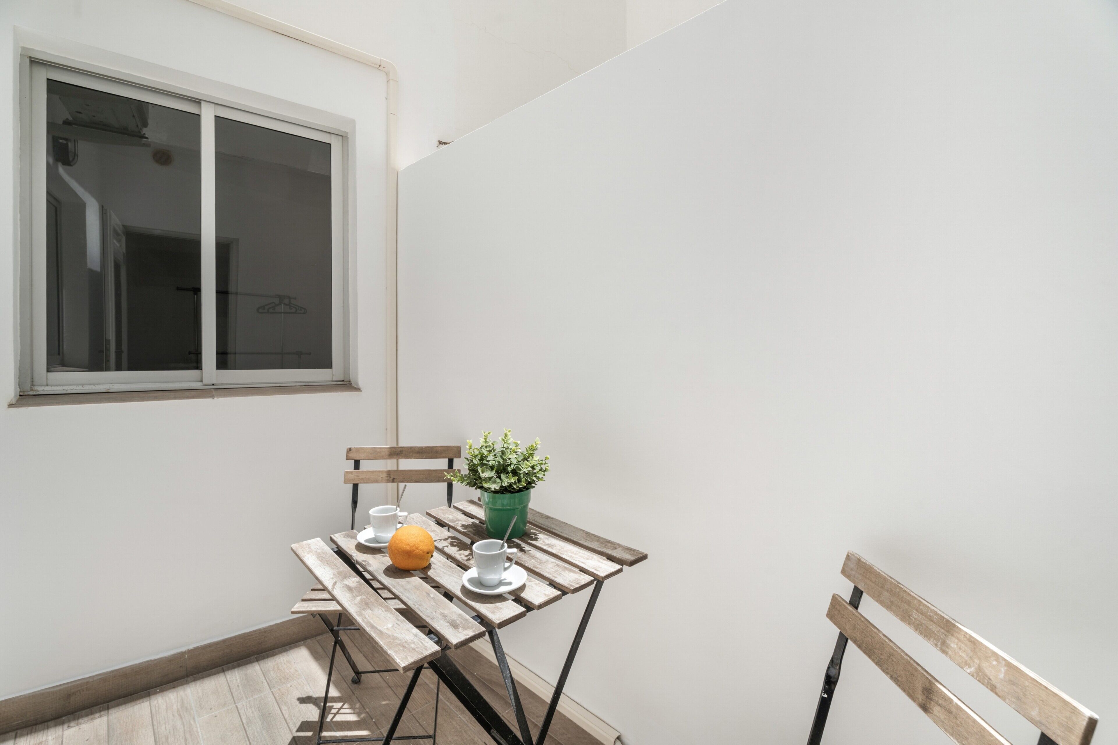 A small outdoor seating area with a table, chairs, and a potted plant.