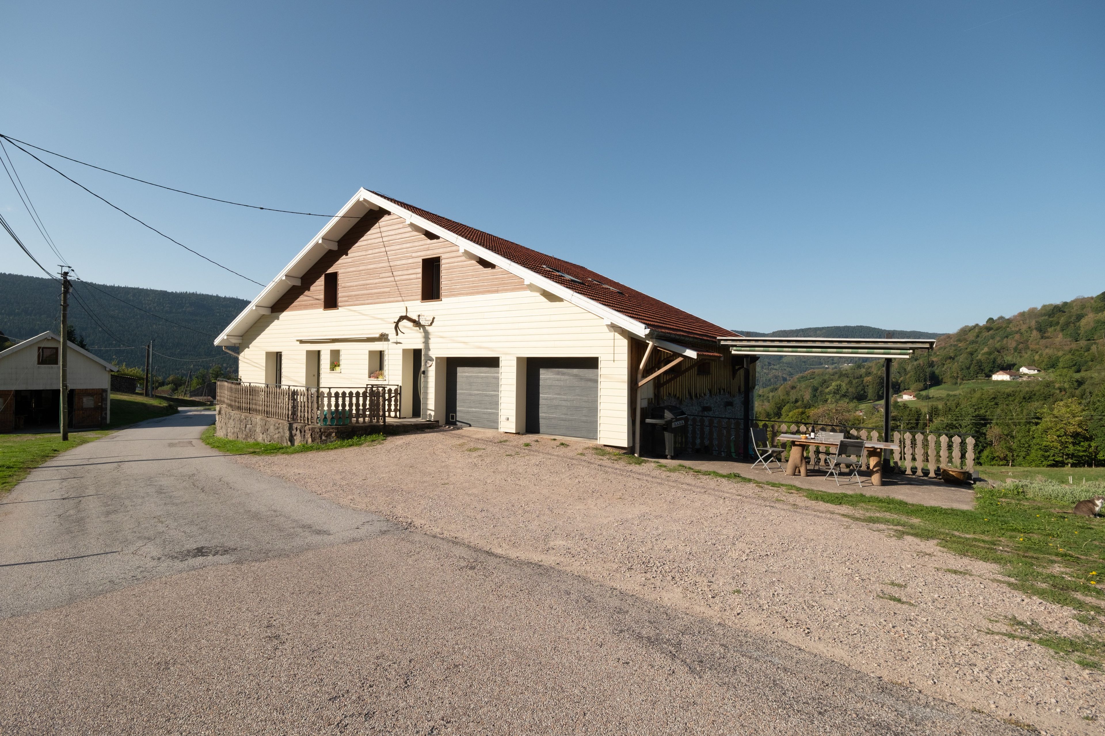 A two-story house with a gravel driveway and a fenced front yard.