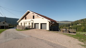 A two-story house with a gravel driveway and a fenced front yard.
