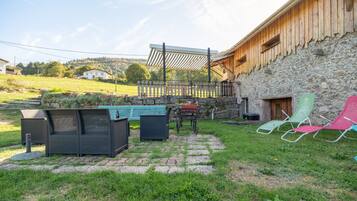 Una zona patio con mobili da esterno, un muro in pietra e un edificio in legno.