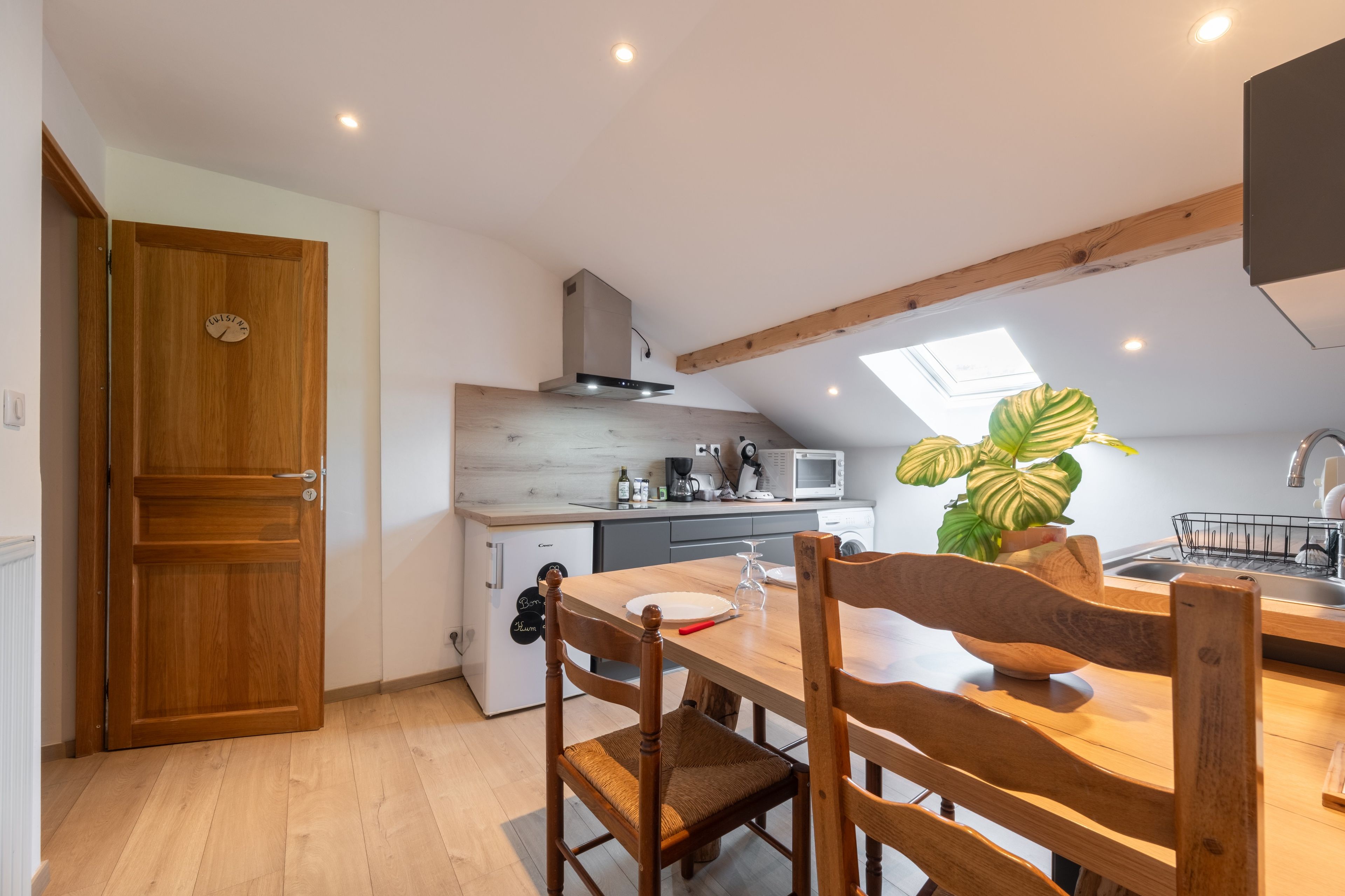 Une cuisine de taille réduite, avec une table en bois, des chaises, un four à micro-ondes et un évier.