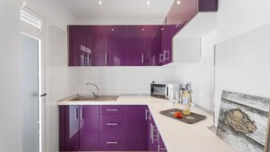 Una cocina moderna con armarios morados, un microondas y una copa de vino.