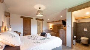 A bedroom with a bed, bedside table, lamp, and a view into the bathroom.