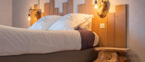 Una cama con cabecera de paneles de madera verticales y lámparas fijadas a la pared.