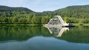 A calm lake with a boat docked on the shore, surrounded by lush green hills.