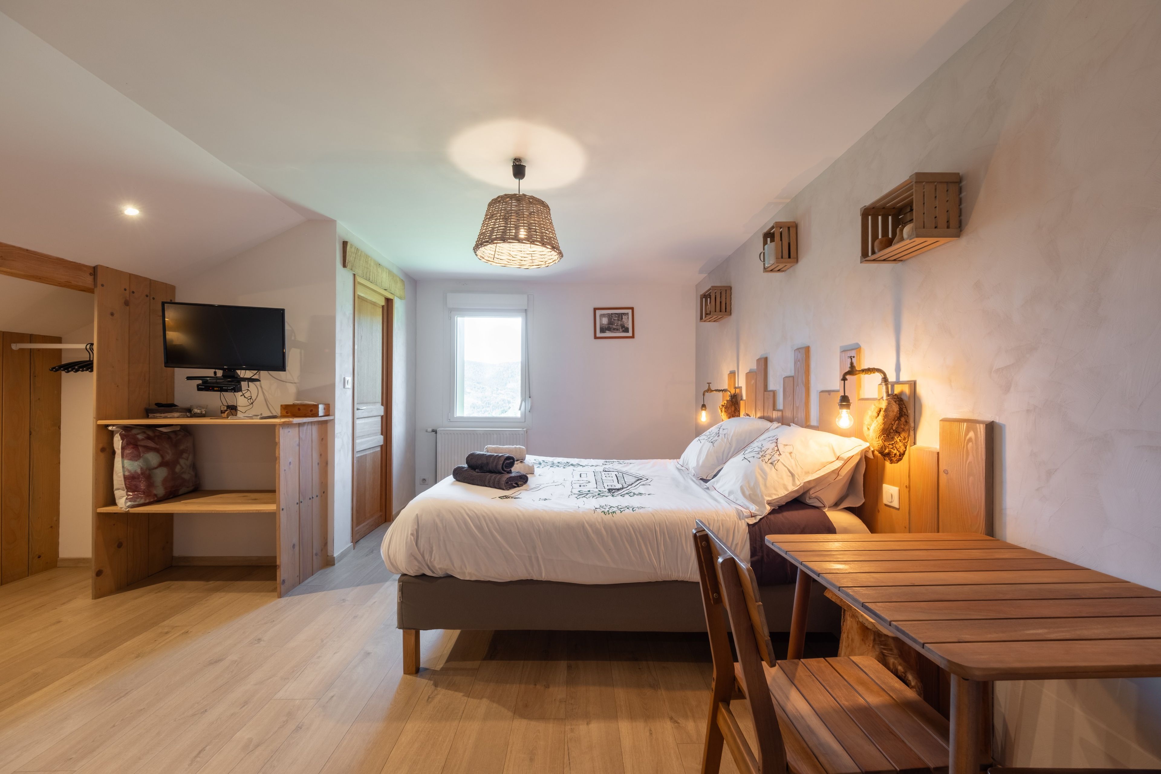 Een slaapkamer met een bed, nachtkastje, stoel, televisie en een raam.