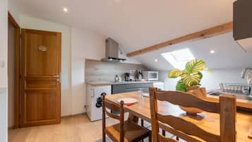 Una cocina compacta con una mesa de madera, sillas, un microondas y un fregadero.