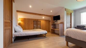 A bedroom with two beds, wooden walls, a television, and a window.