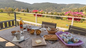 A table set outdoors with food, drinks, and a scenic view of mountains.